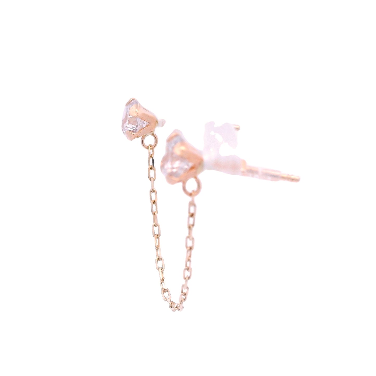 Side angle view of two round white zirconia studs with a 14k yellow gold base. They are connected by a thin yellow gold chain.