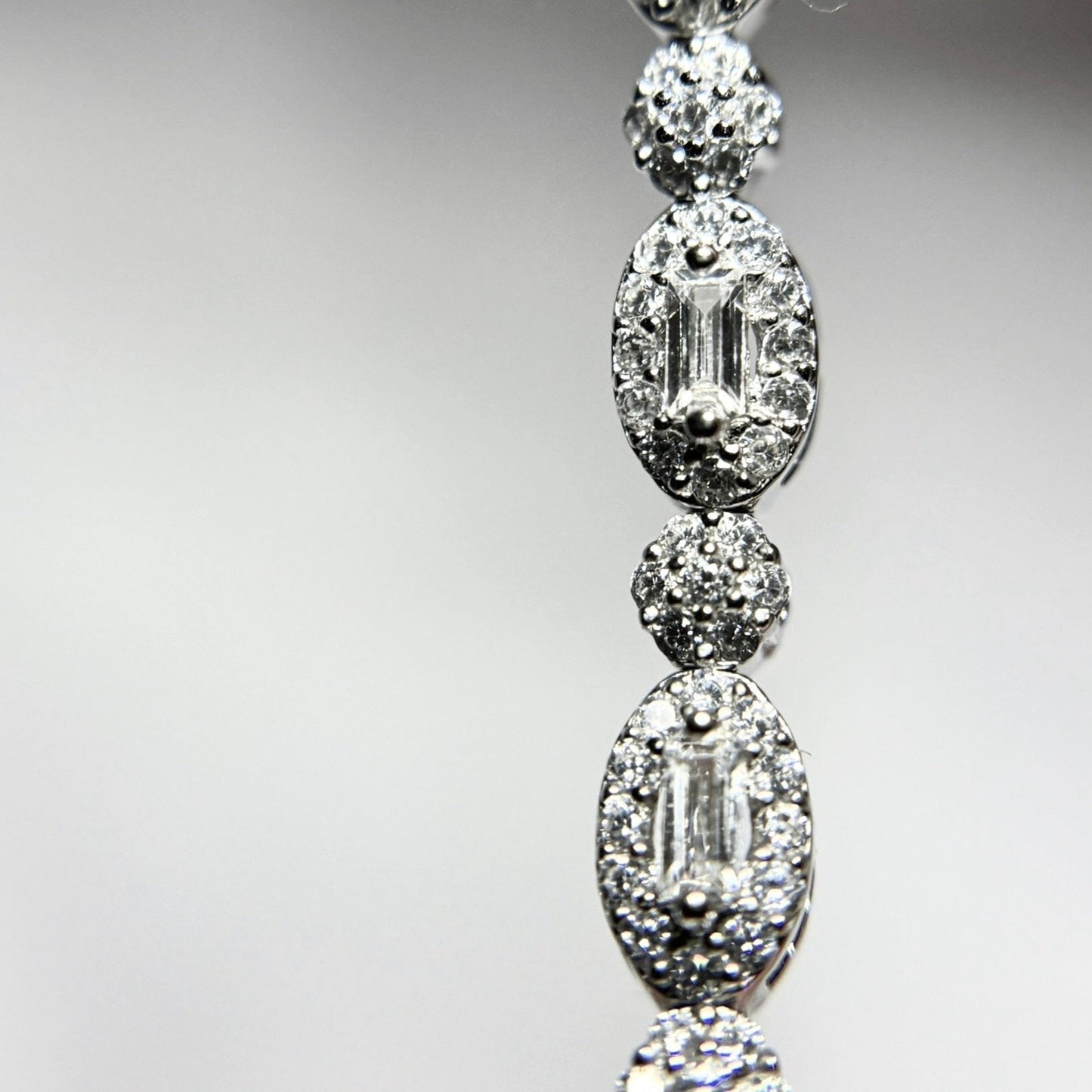 Silver Vintage Bracelet on white background close up. Pearl shaped with baguette zirconia in the center and pave pieces around it. Pattern of pearl piece and round pave one.