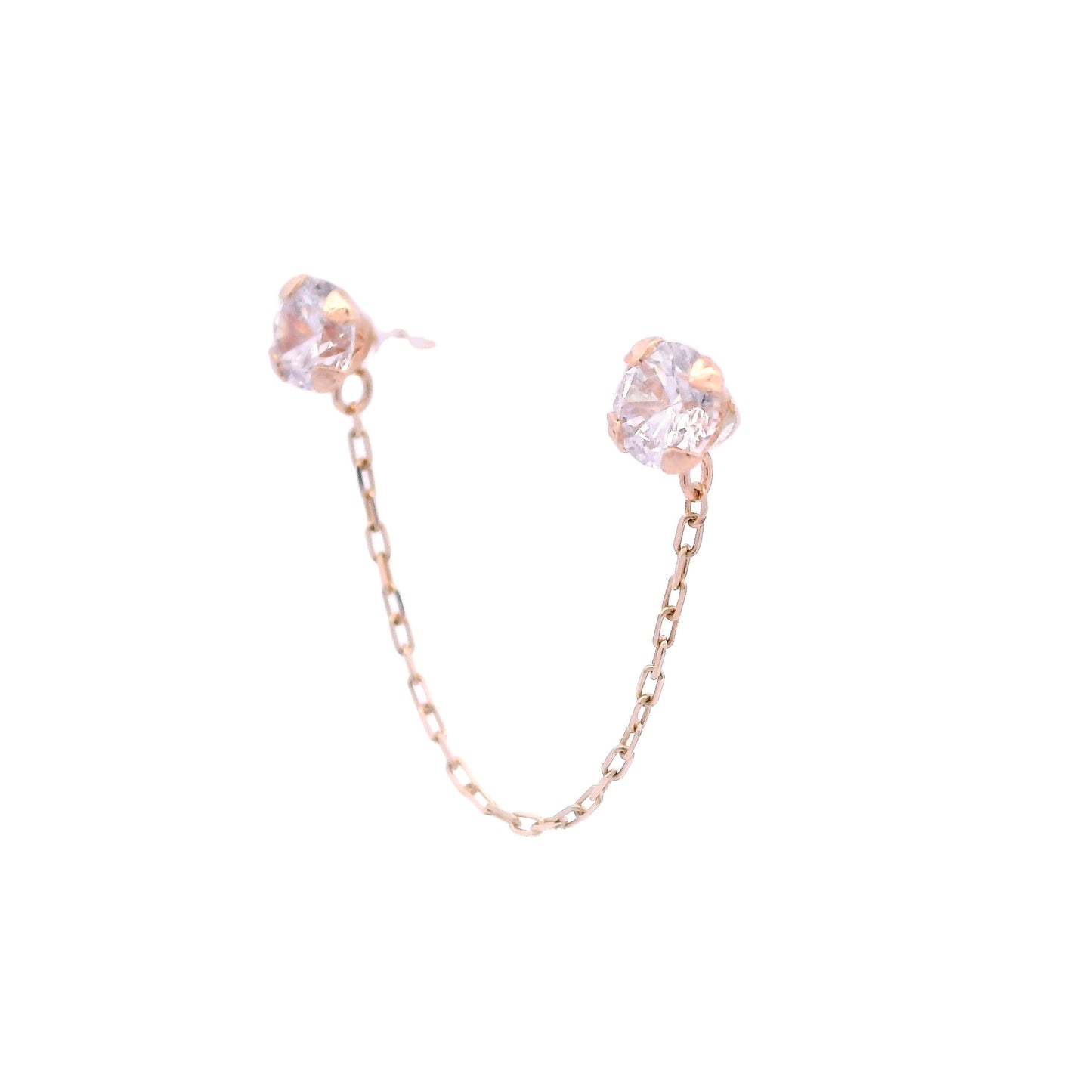 Side angle view of two round white zirconia studs with a 14k yellow gold base. They are connected by a thin yellow gold chain.