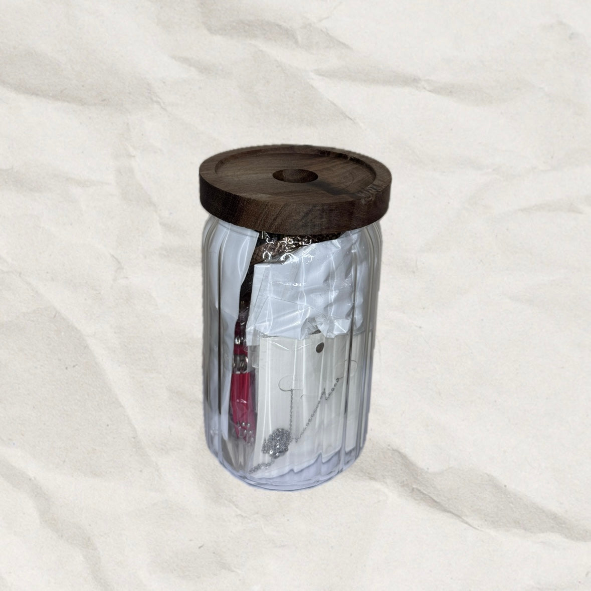 Medium, clear tumbler with wooden lid on a white background. The tumbler is filled with jewelry.