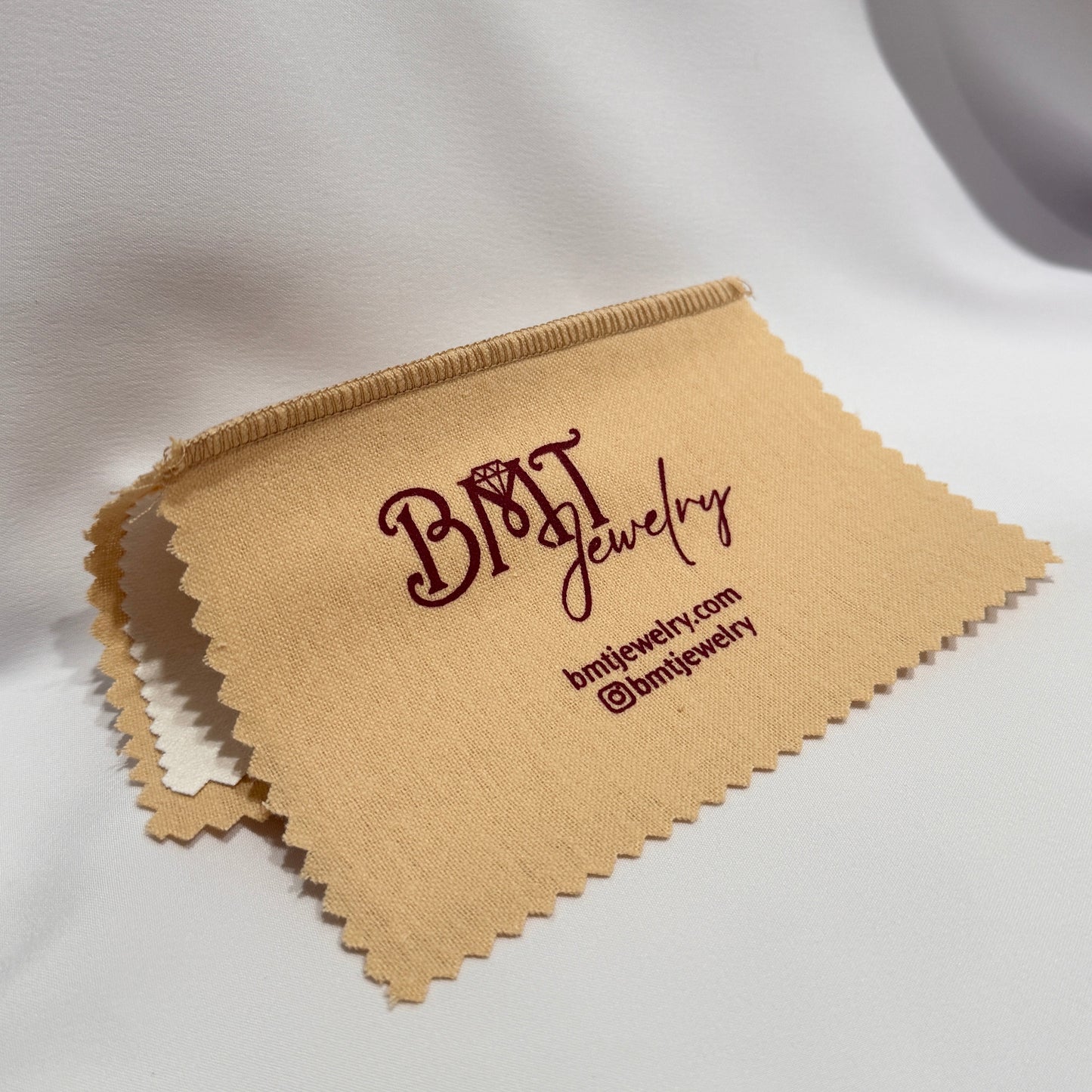 Brown jewelry cleaning cloth with 'BMT Jewelry' branding on a white background