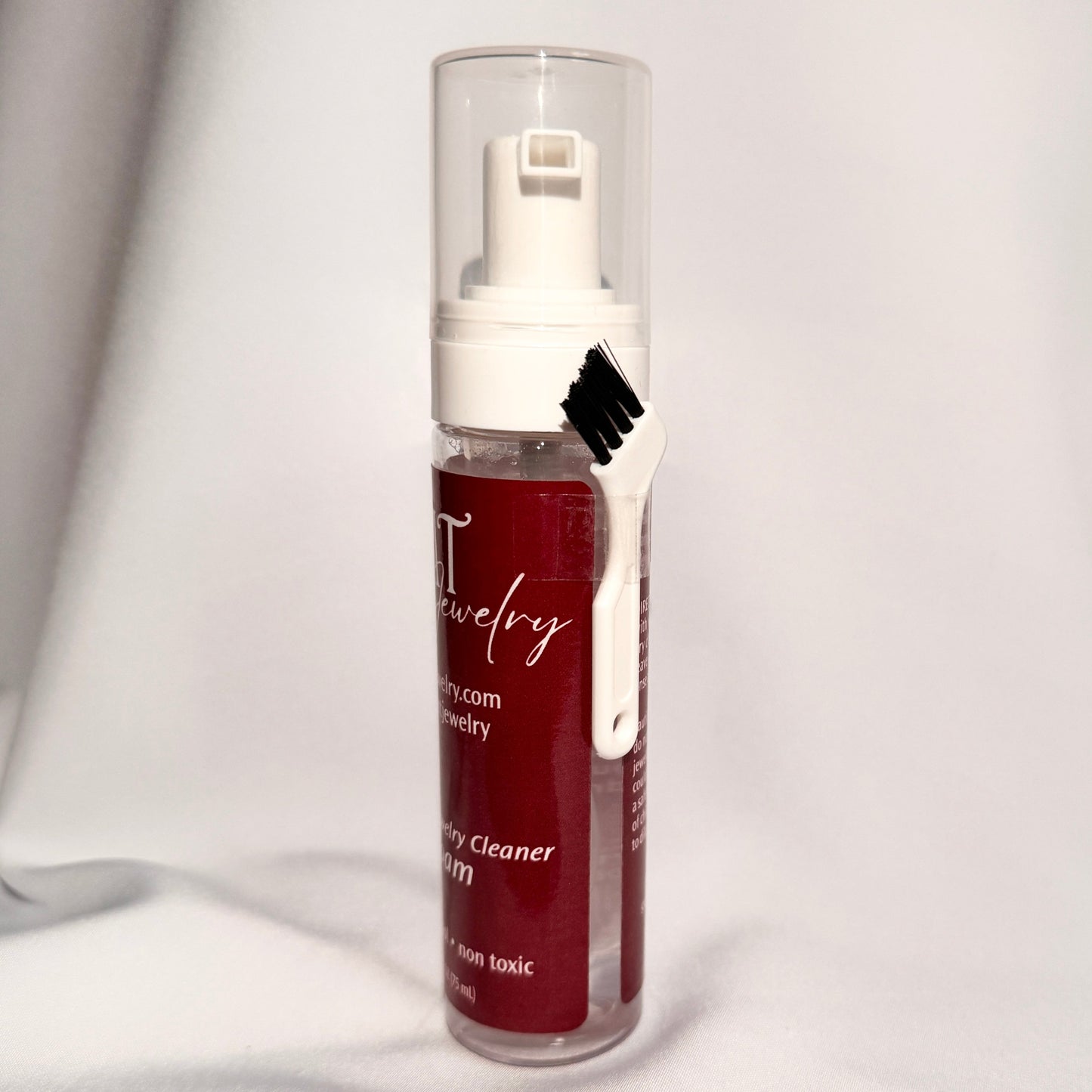 Bottle of jewelry cleaner with a white pump on a white background