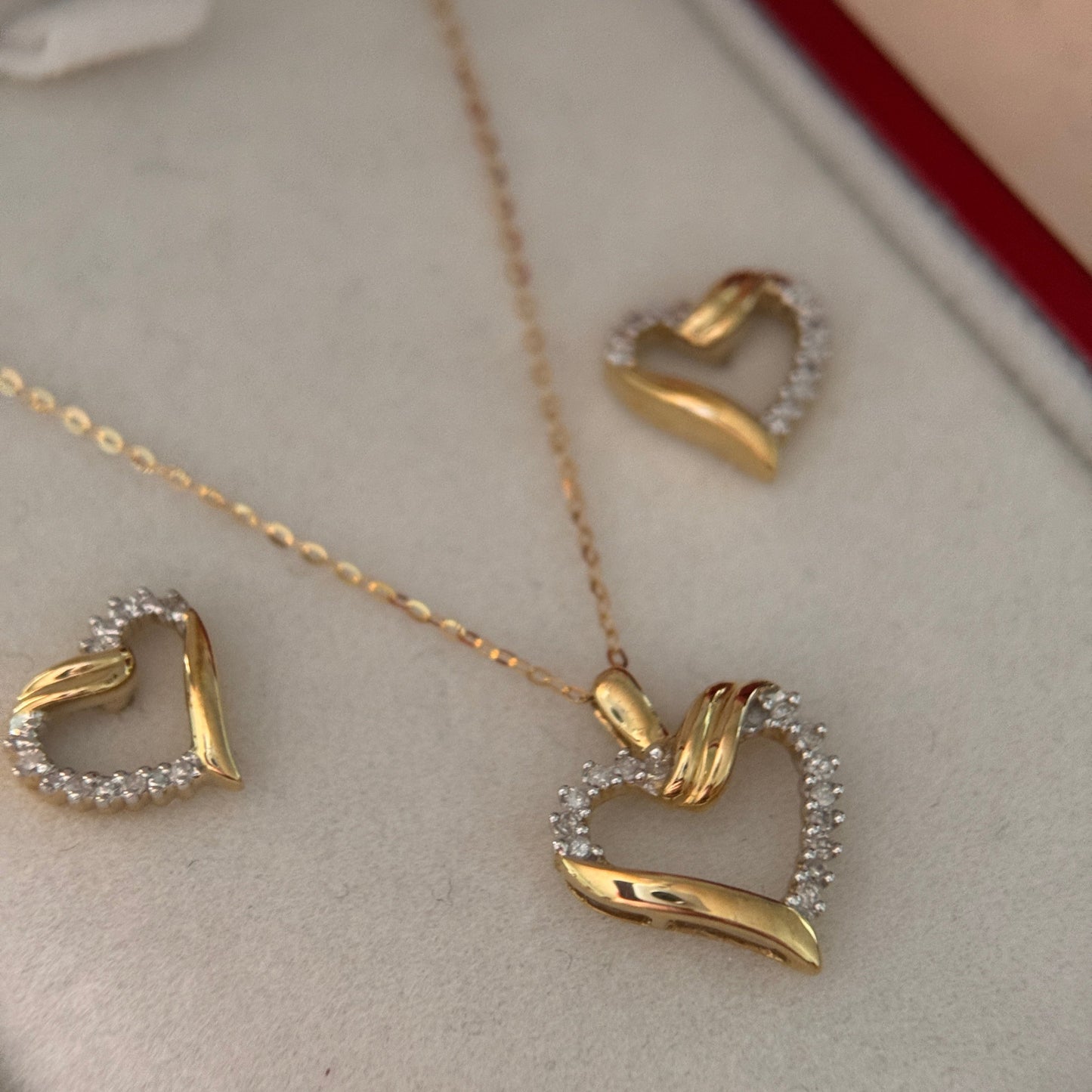 Zoomed in image of the 10k Yellow gold heart set. The hearts have an intricate design with white diamond on the top right side of the heart and bottom left side of the heart.