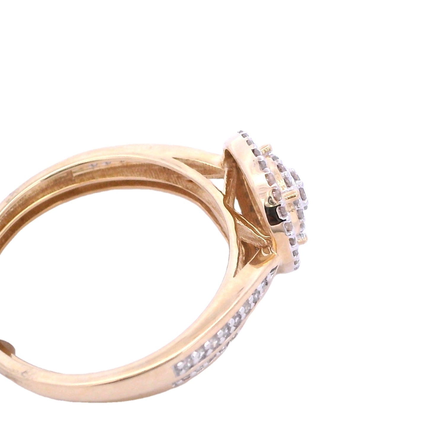 Angled aerial view of yellow gold bridal set. The center of the engagement ring is round, it has 2 tiers filled with small round diamonds. Then there is an empty space followed by a thin round gold outline. Outside of the outline there is a halo made up of round diamonds. The bands pinch at the center and expand to fill the sides with round diamonds. The wedding band has round diamonds in the front and sides. It follows the shape of the engagement ring.