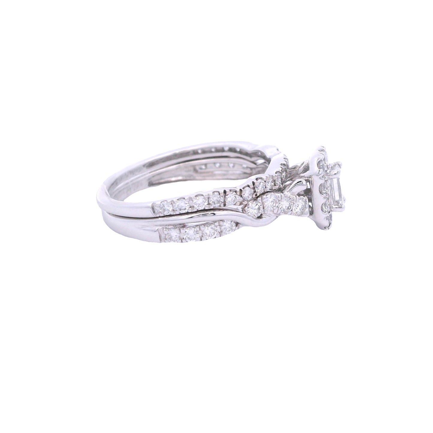 Side view of white gold bridal set. The engagement ring has a baguette diamond in the center and a rectangular halo made up of round zirconia. The engagement ring band has a twist effect with two thin bands: a solid and pave diamond one. The wedding band is laying on top and has pave diamonds. It matches the shape of the engagement ring.
