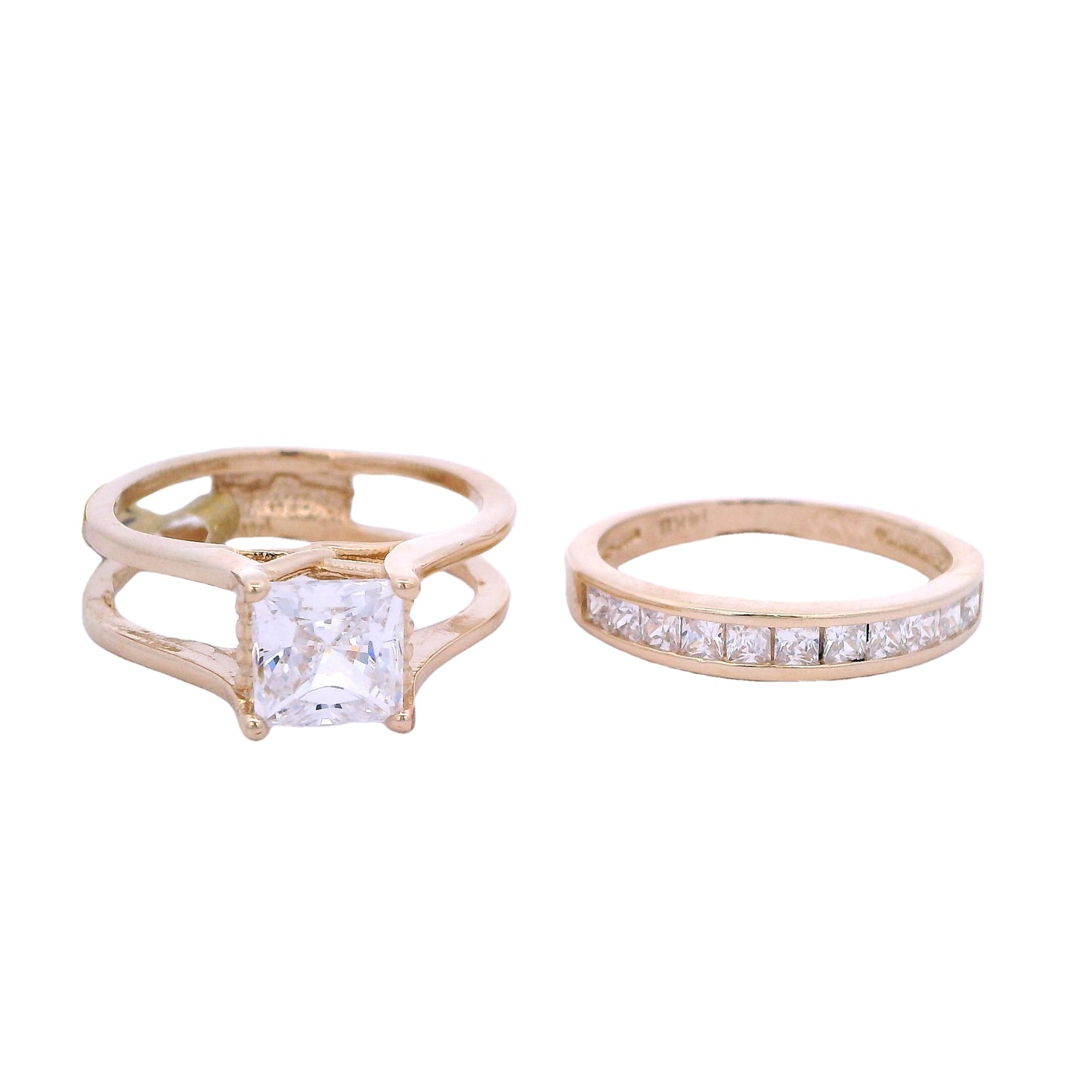 Front view of yellow gold bridal set. The engagement ring is on the left side of the screen. Its has a princess cut white zirconia with 4 prongs, one on each corner. Each band curves into a solid band creating 2 bands on each side of the zirconia and connecting in the back. On the right of the screen there is a wedding band with small princess cut white zirconia in the front.