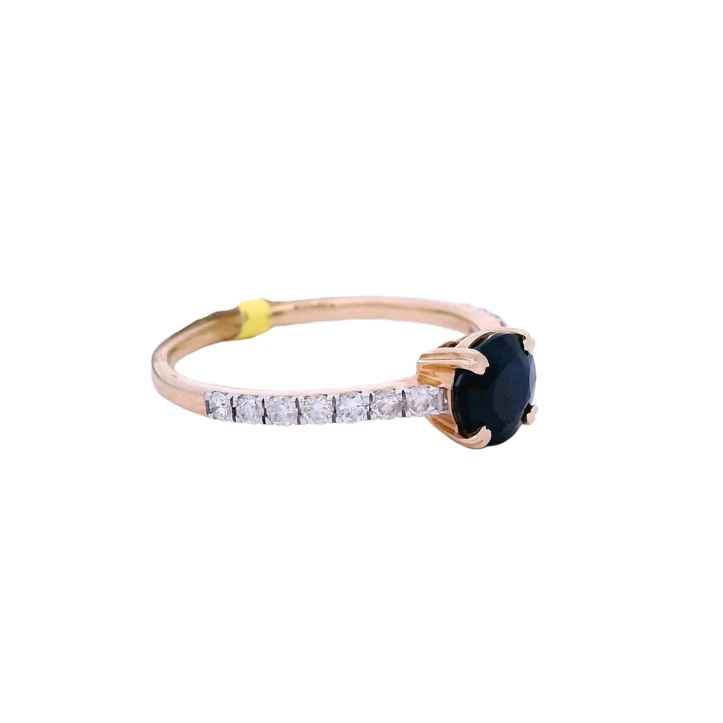 Side view of yellow gold ring with a round blue sapphire in the center. The sapphire is held by 4 yellow gold prongs. There are white round zirconia on both sides of the band.
