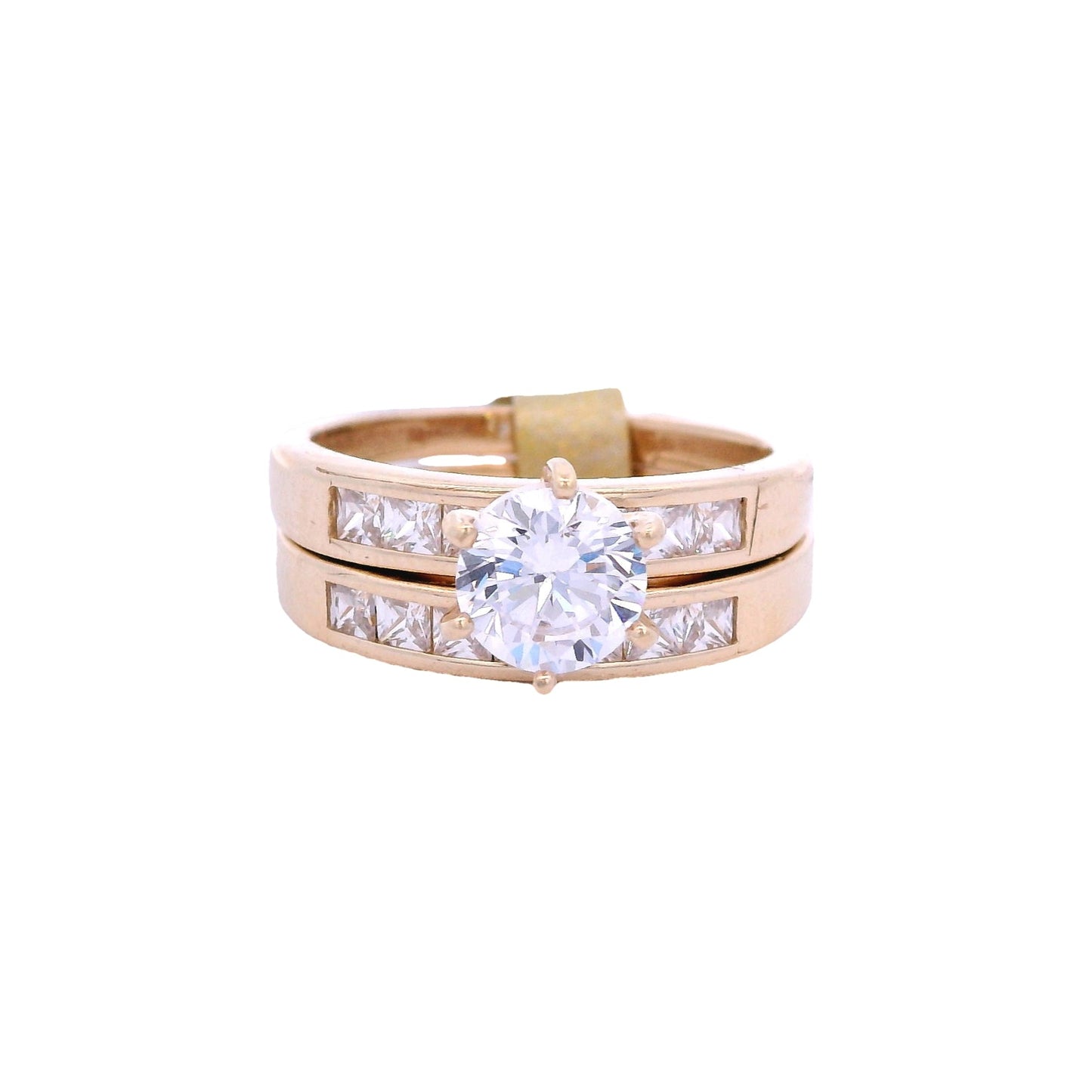 Front view of yellow gold engagement ring and wedding band. The engagement ring has a round white zirconia in the center and white princess-cut zirconia on each side. The wedding band has white princess-cut zirconia in the center.
