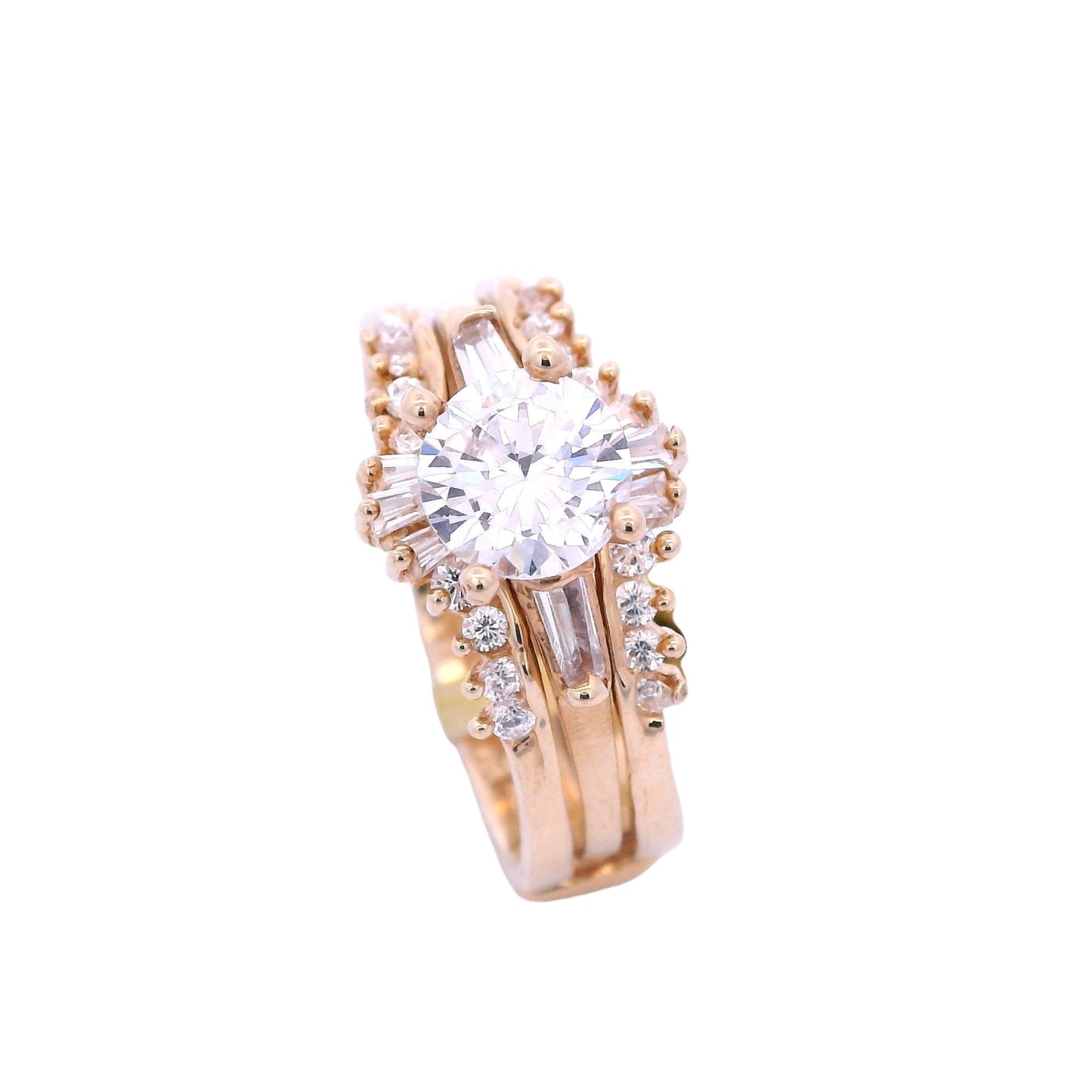 Angled view of yellow gold ring with enhancer. The engagement ring has a single white zirconia in the center and 2 white baguette zirconia on each side. The enhancer has graduated baguettes in the center and round white zirconia on the sides.