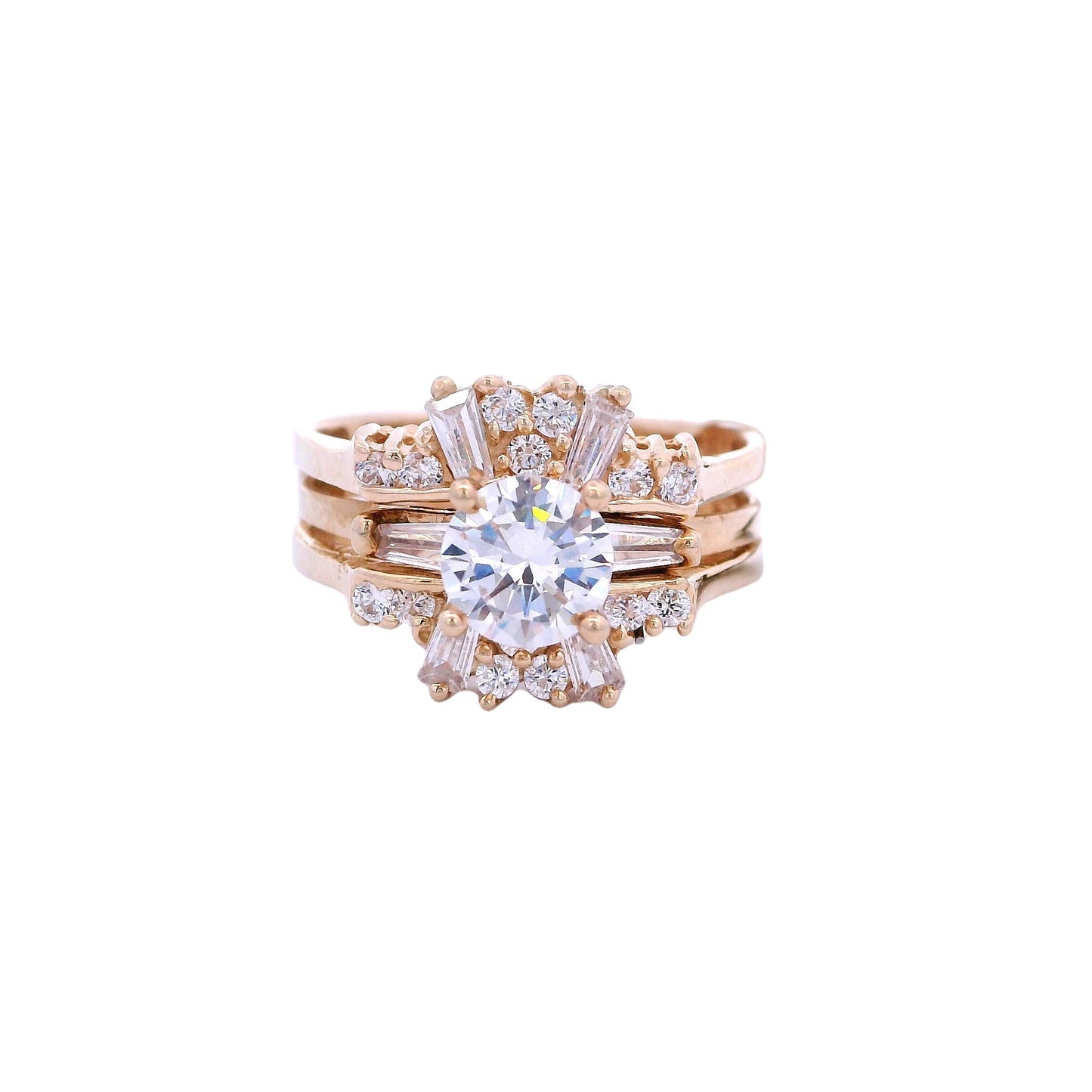 Front view of gold bridal ring. The engagement band has a single white zirconia with a baguette zirconia on each side. The ring is inside a ring enhancer that has round and baguette white zirconia.