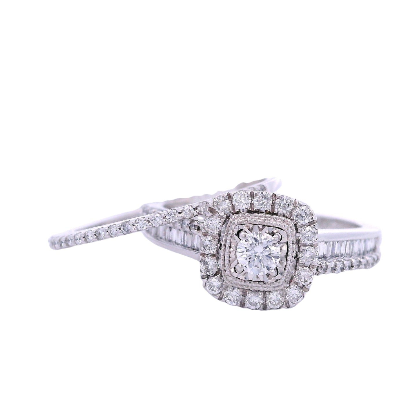 Front view of white gold bridal set. The engagement ring has a round diamond in the center with a rectangular halo that is lined with round pave diamonds. The ring also has a band with a row of round pave diamonds and a row of baguette diamonds. There is a thin wedding band with round pave diamonds on laying at an angle on the engagement ring to the left of the screen.