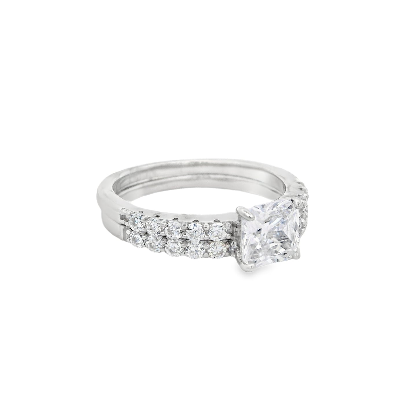 Side view of Silver bridal set. The wedding band is on the right and it has round zirconia in a pave setting. The engagement ring is on the left and it has a single square zirconia in the center and round zirconia on each side in pave setting.