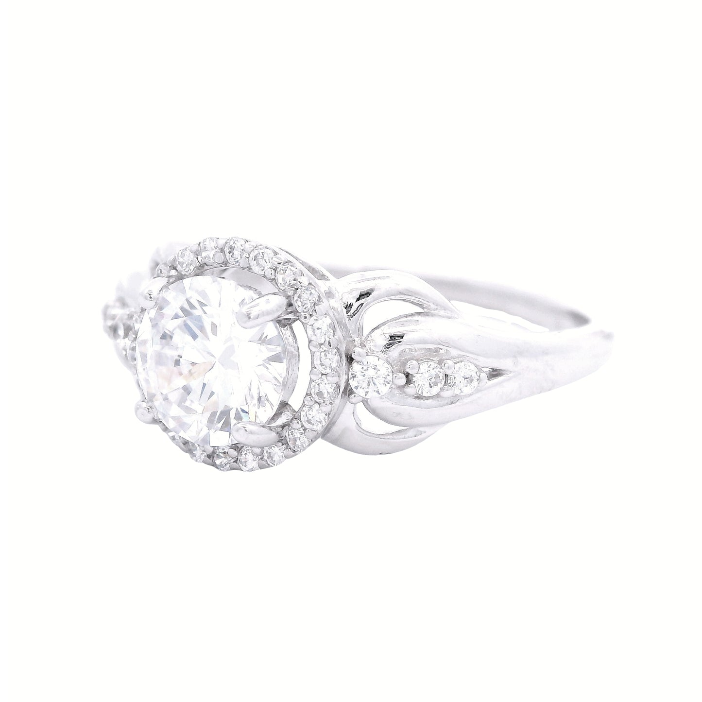 Angled view of sterling silver ring with round-shaped zirconia in the center and a round halo. It has decorative swirls with round zirconia accents on each side.