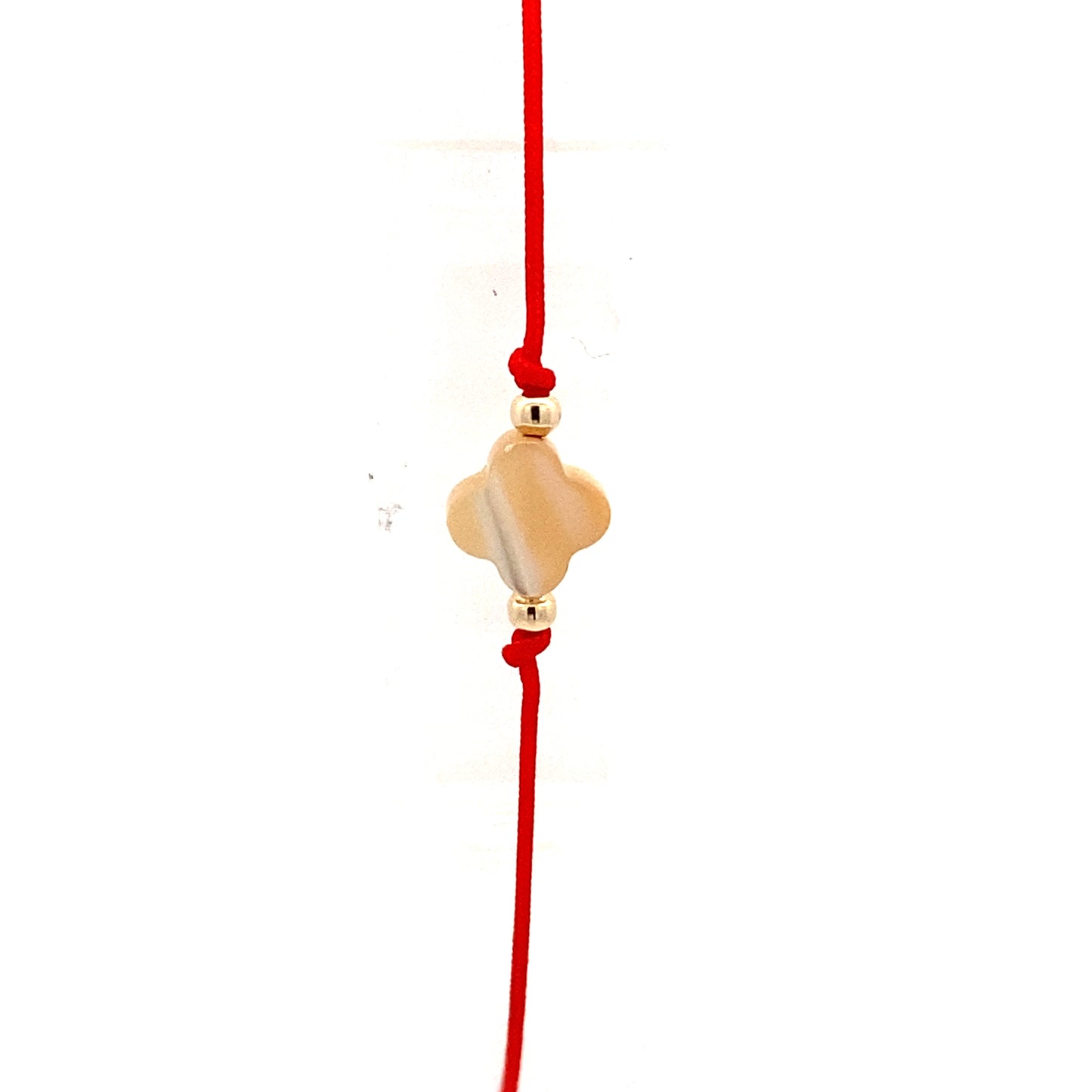Handmade adjustable red string bracelet with a Mother of Pearl clover in the center and 2 gold beads on each side. Close up.