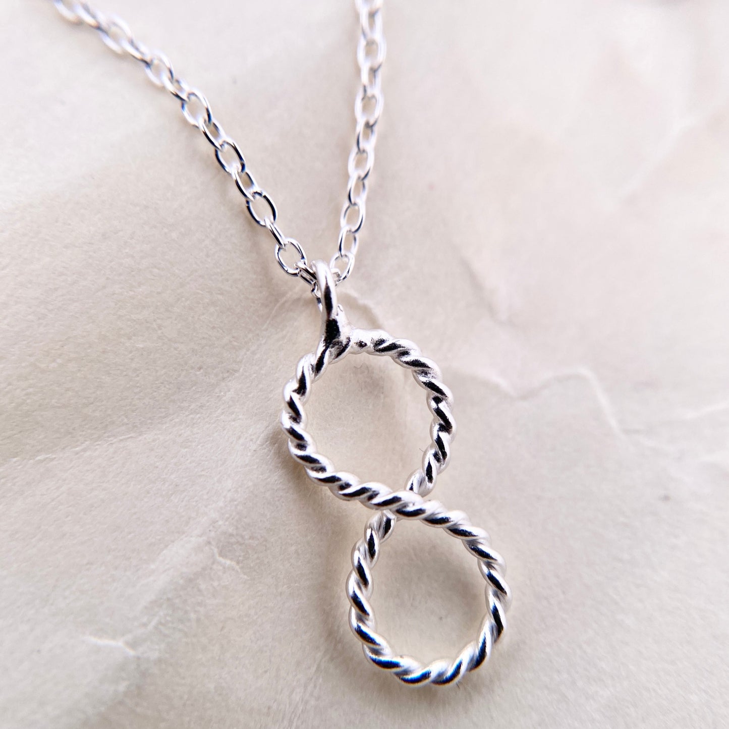 Silver vertical Infinity Pendant with rope texture and accompanying necklace. Pendant Close up.