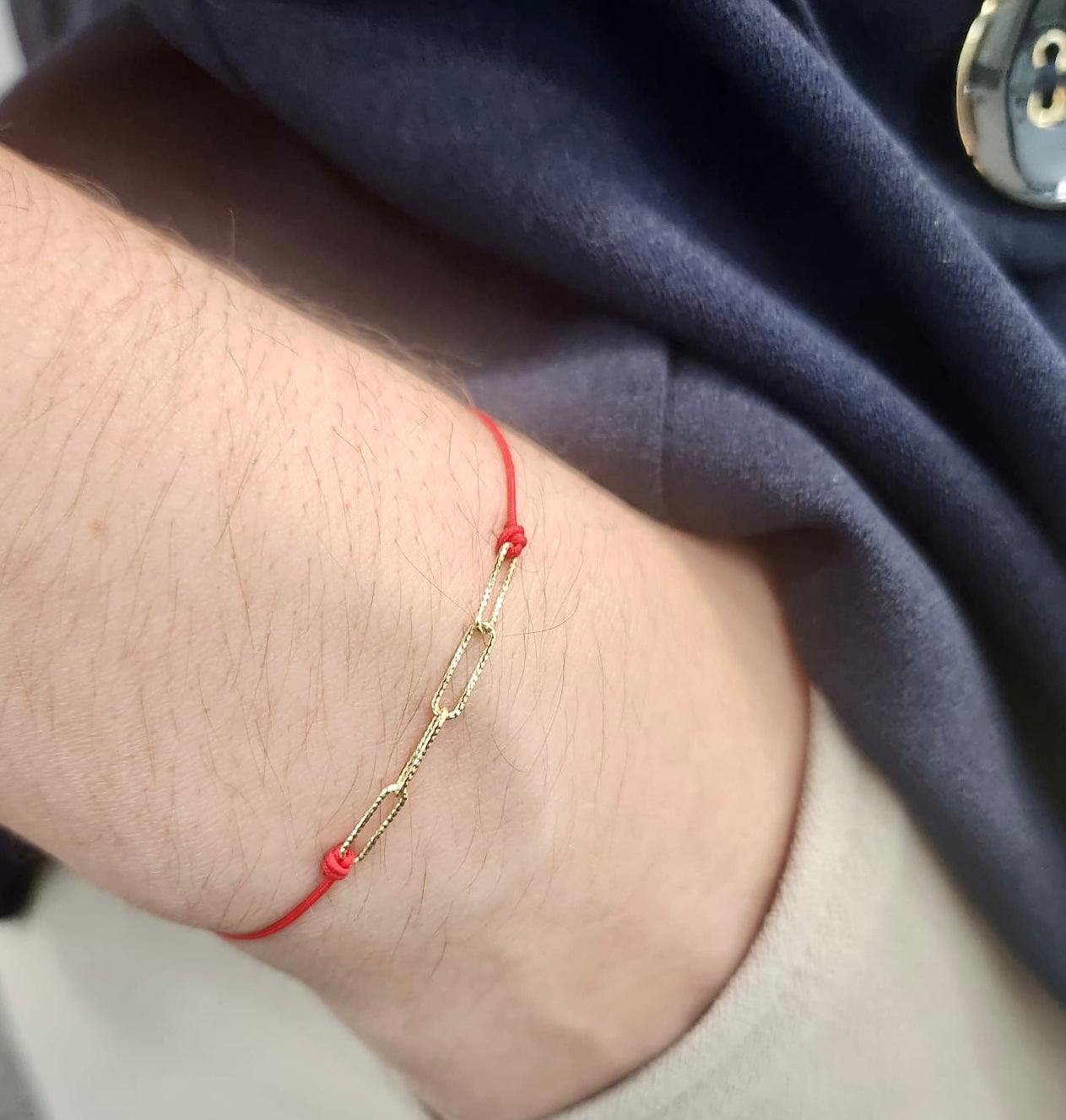 Model wearing red chain bracelet with hand in pocket