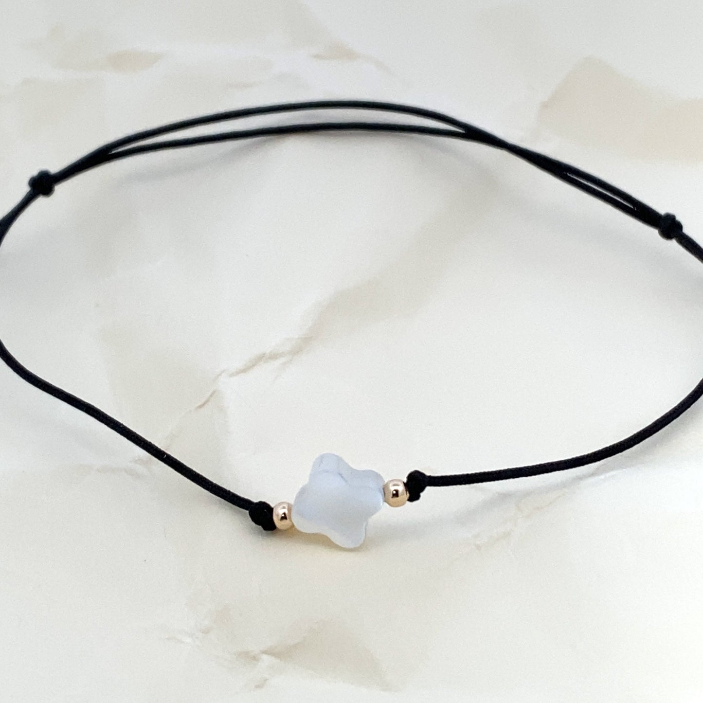 Handmade adjustable black string bracelet with a Mother of Pearl clover in the center and 2 gold beads on each side. Full bracelet