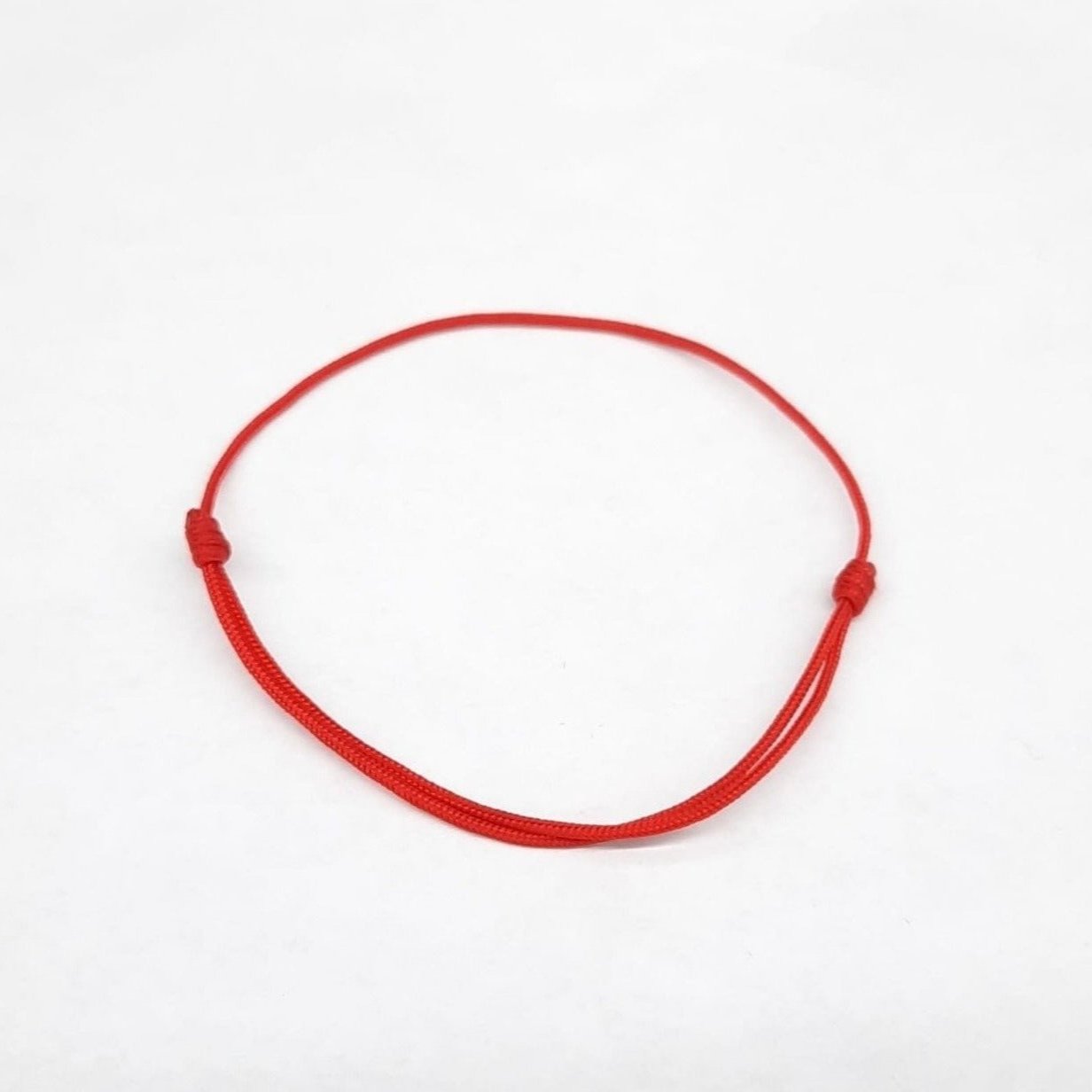 Top view of Simple red string bracelet with two knots on each side to adjust the bracelet size.