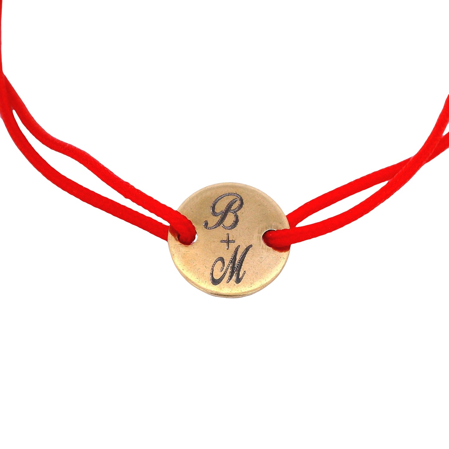 Close up of Red string bracelet with a round yellow stainless steel featuring the initials "B" and "M" with a plus sign in the middle on a white background