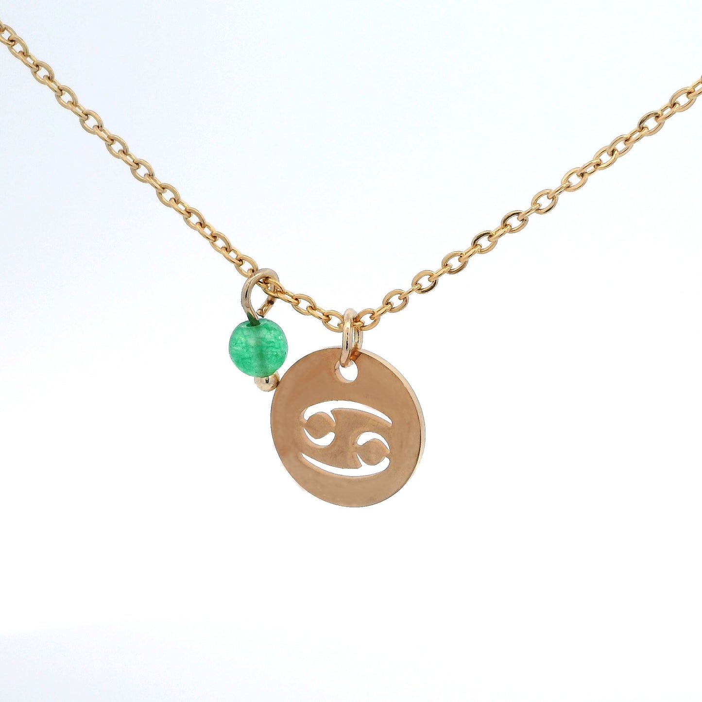 A gold-plated stainless steel chain necklace with a round gold disc pendant featuring a cutout symbol of the Cancer zodiac sign, adorned with a small bead, on a white background.