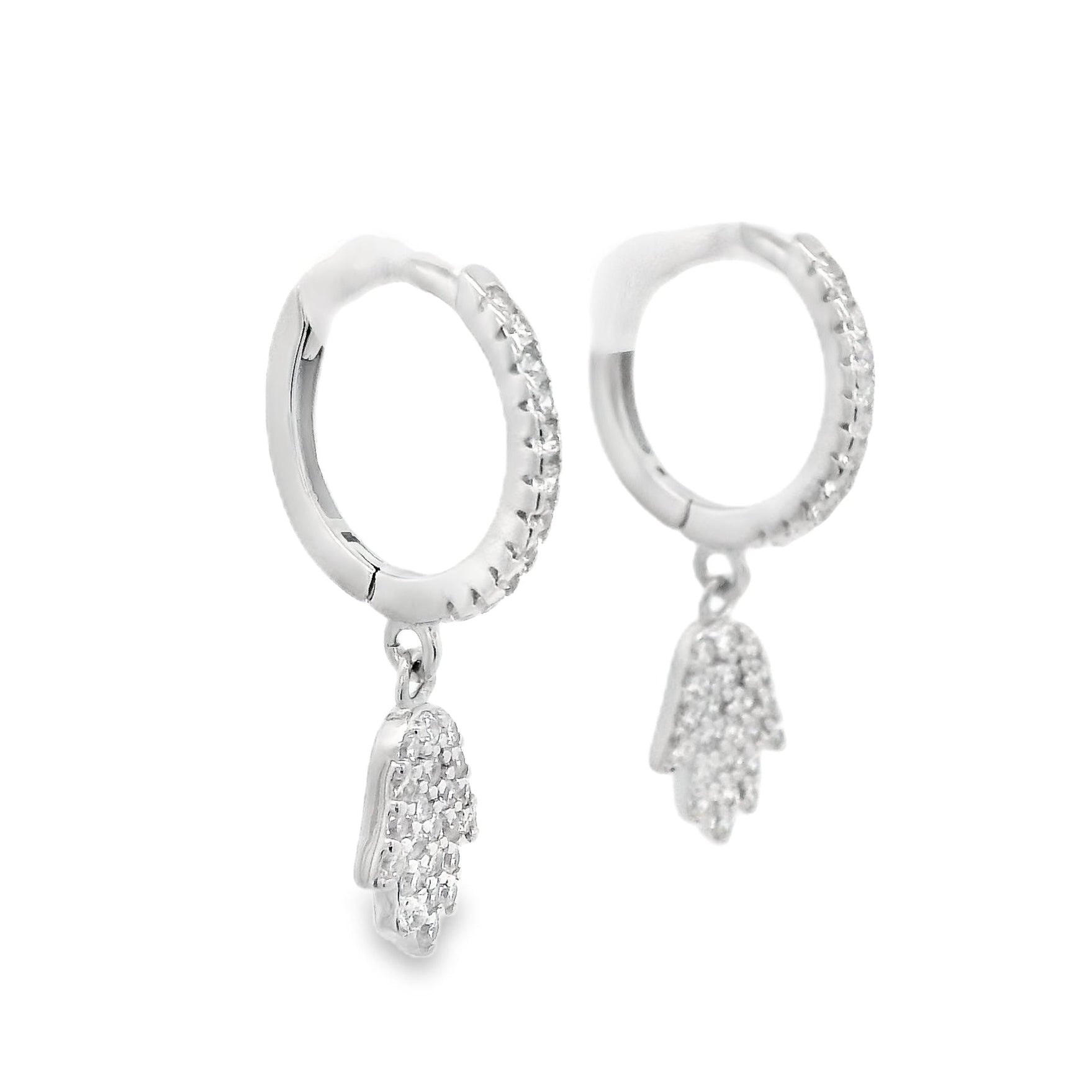 Angled side view of silver hoops with round clear zirconia and a hamsa hand that dangles below each huggie that also has round zirconia inside it.