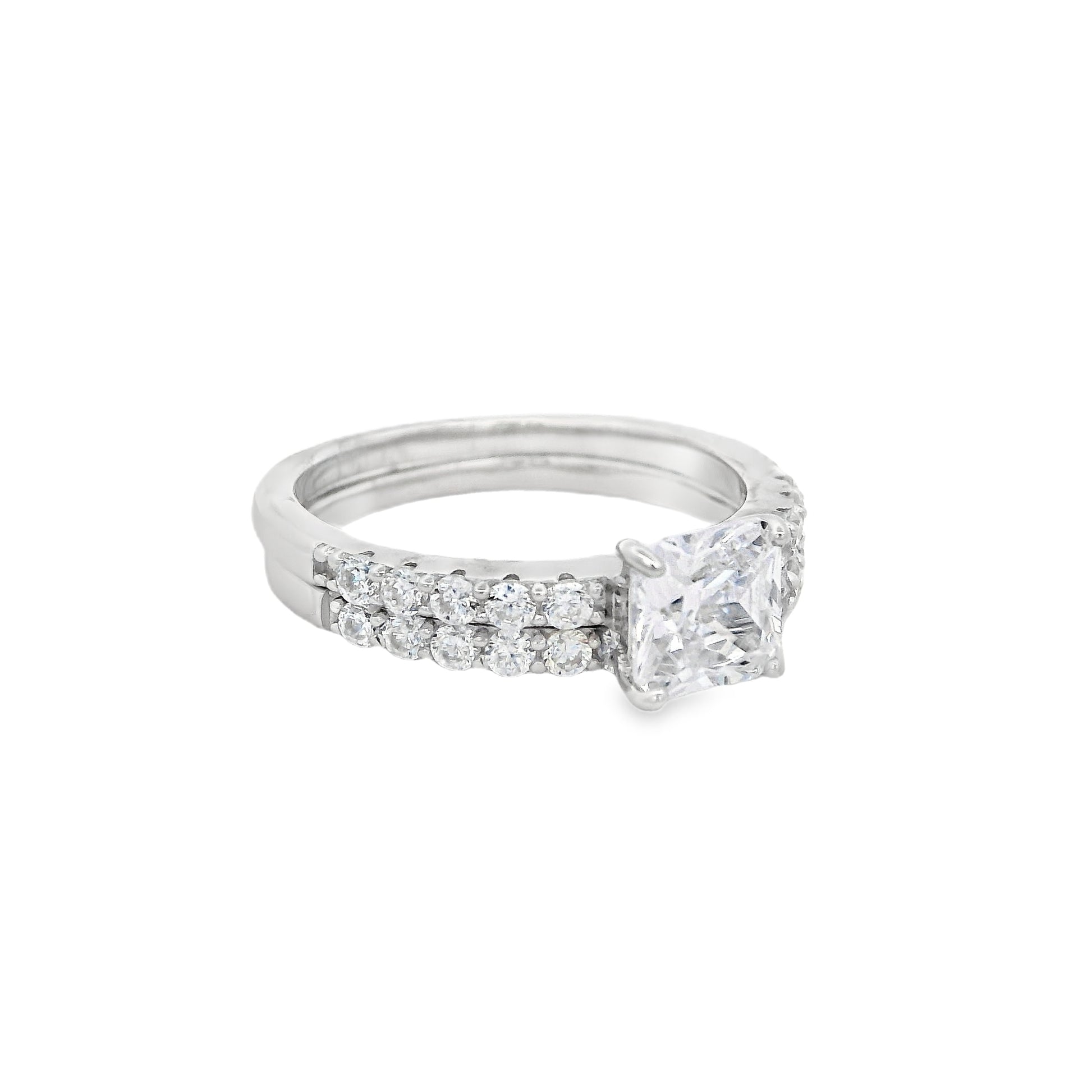 Side view of Silver bridal set. The wedding band is on the right and it has round zirconia in a pave setting. The engagement ring is on the left and it has a single square zirconia in the center and round zirconia on each side in pave setting.