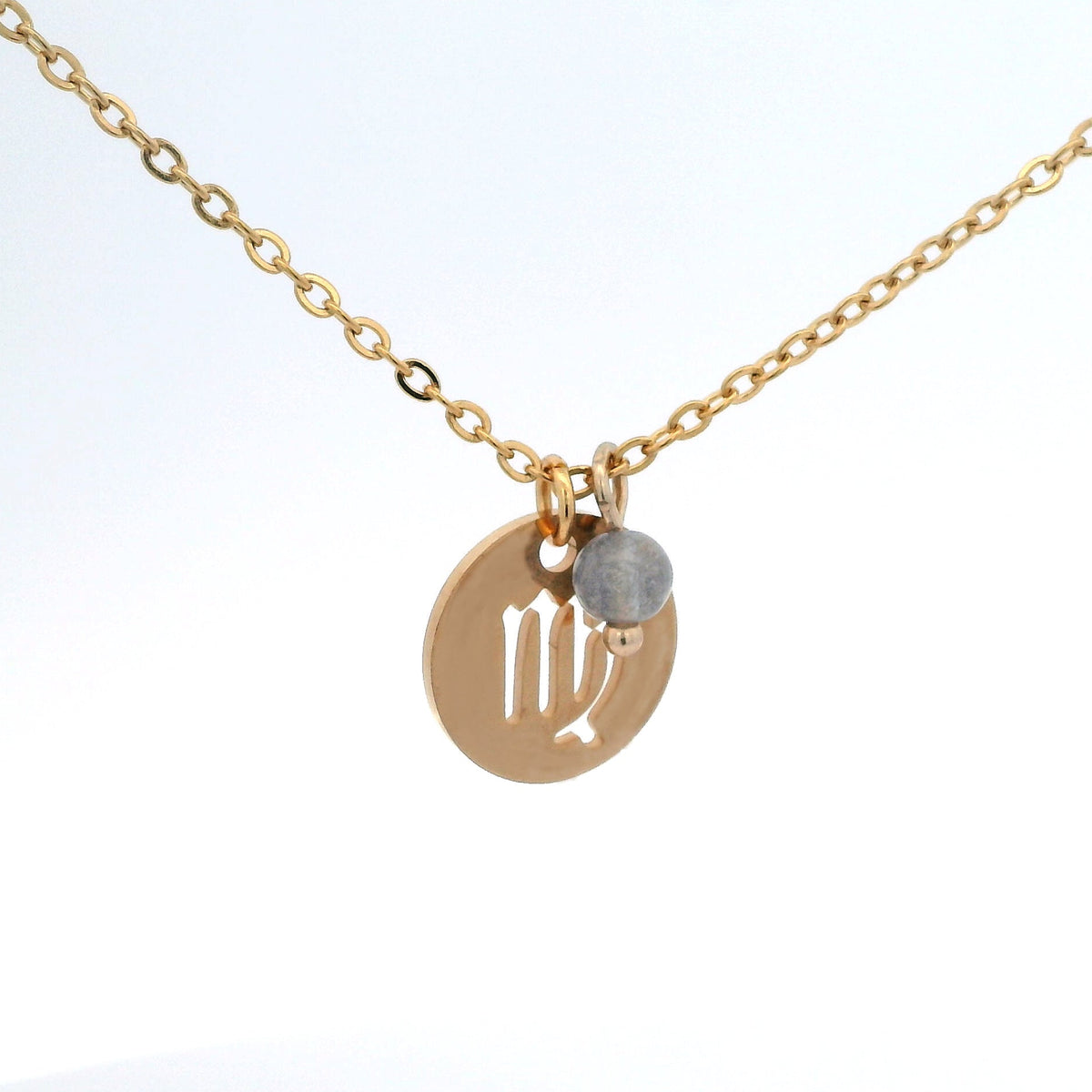 A gold-plated stainless steel chain necklace with a round gold disc pendant featuring a cutout symbol of the Virgo zodiac sign, adorned with a small bead, on a white background.