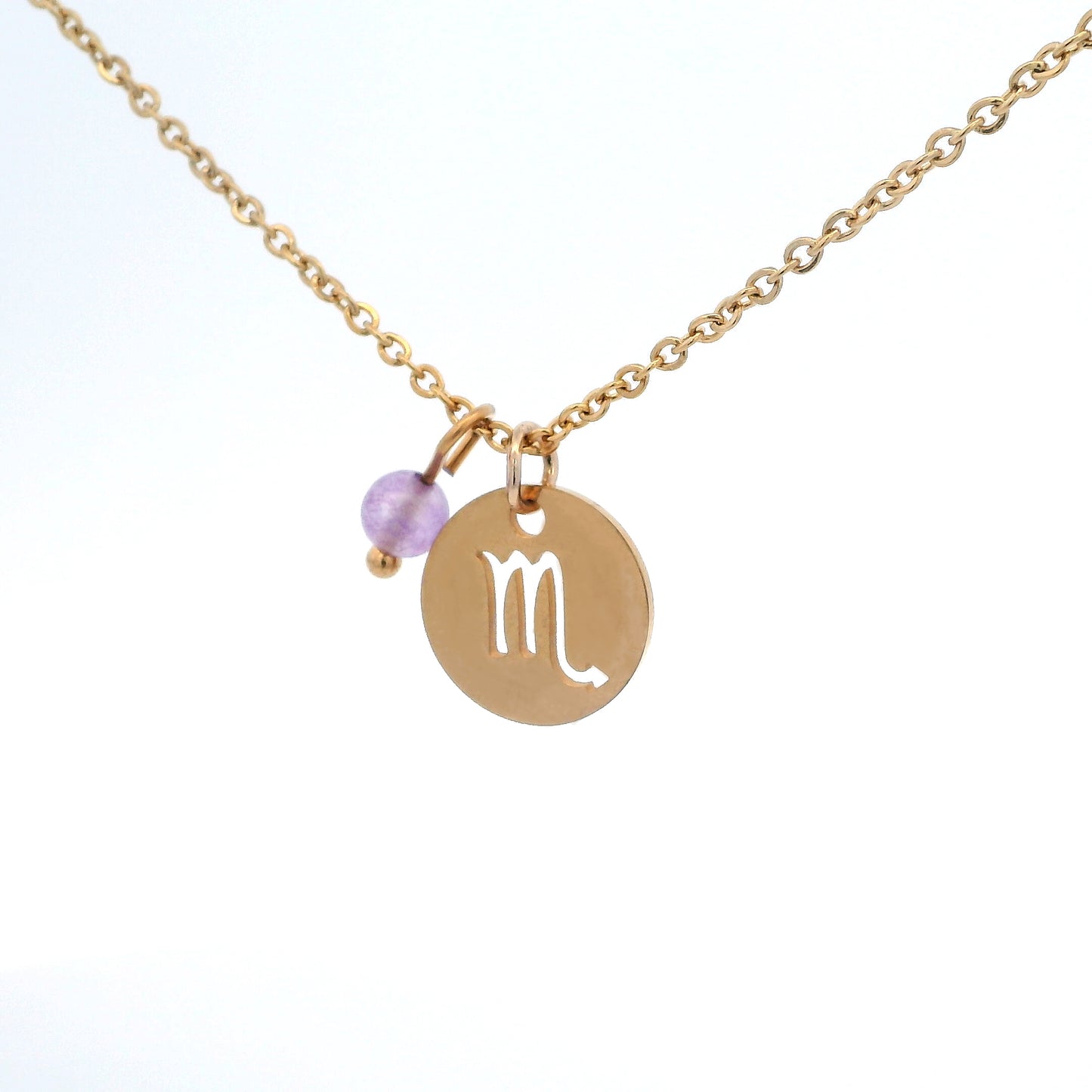 A gold-plated stainless steel chain necklace with a round gold disc pendant featuring a cutout symbol of the Scorpio zodiac sign, adorned with a small bead, on a white background.