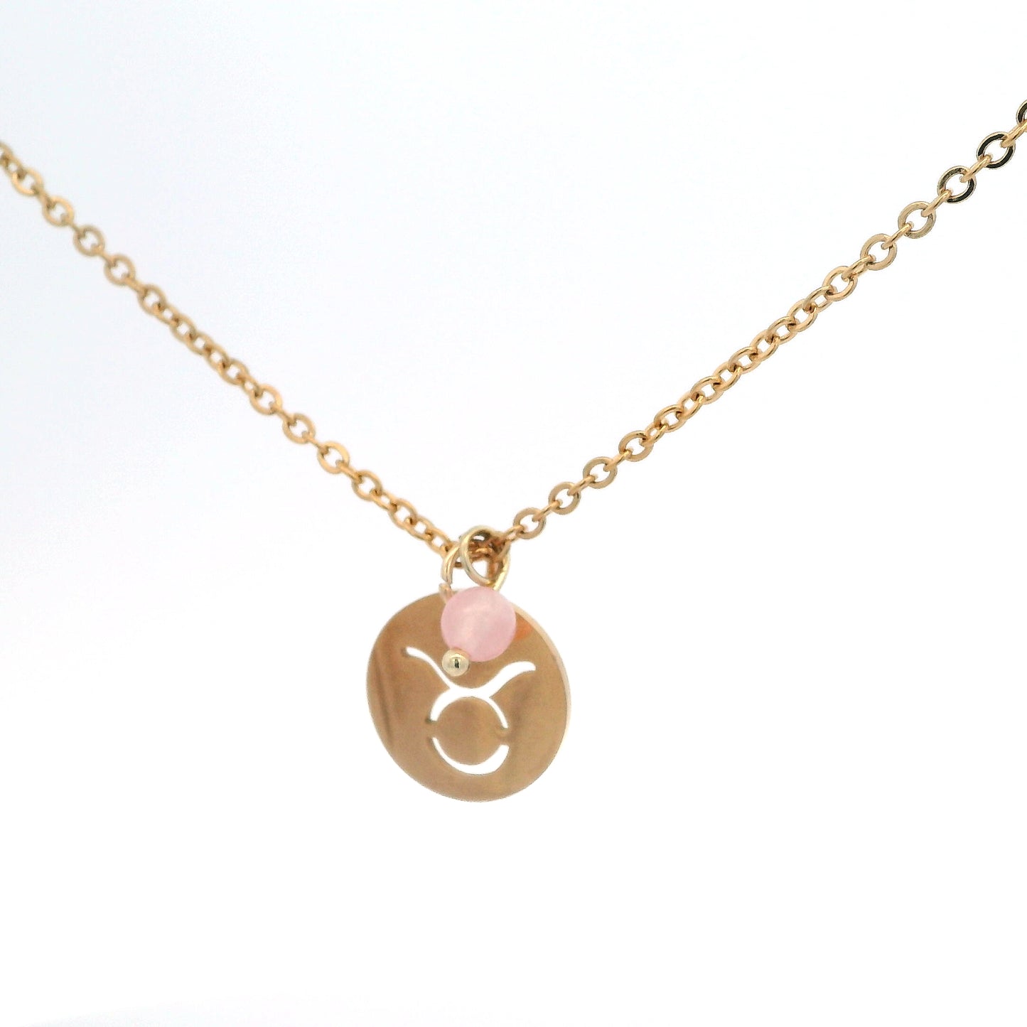 A gold-plated stainless steel chain necklace with a round gold disc pendant featuring a cutout symbol of the Taurus zodiac sign, adorned with a small bead, on a white background.